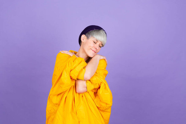 Stylish european woman on purple background self care hugging herself with smile and closed eyes - Φωτογραφία, εικόνα