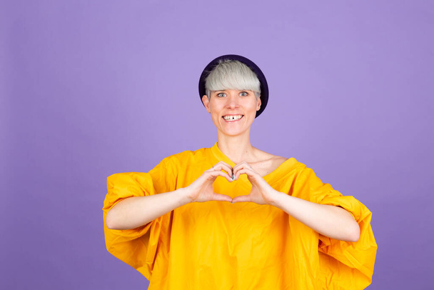 Stylish european woman on purple background shows heart with hands love concept copy space - Fotoğraf, Görsel