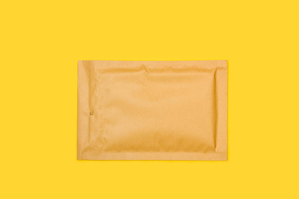 Ein braun gepolsterter Umschlag auf gelbem Hintergrund - Foto, Bild