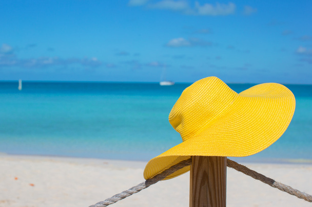 Keltainen hattu aidan trooppisella valkoisella rannalla
 - Valokuva, kuva