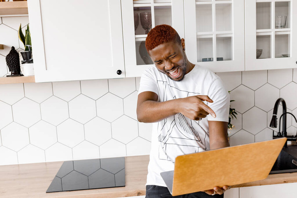 african american man with laptop  in kitchen - Foto, imagen