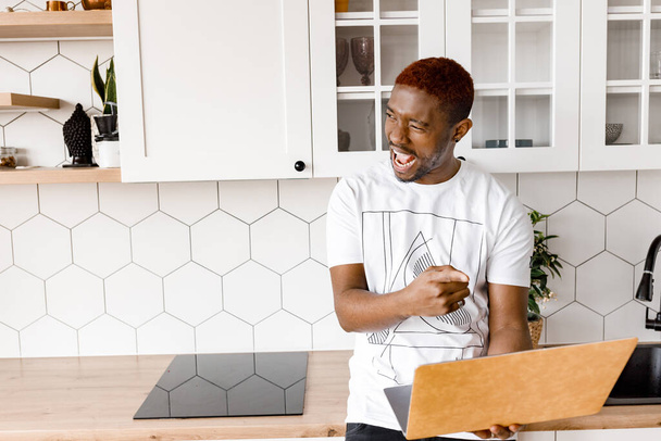 african american man with laptop  in kitchen - Foto, Imagen