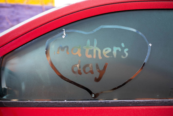 äitienpäivä kirjoitettu punaisen auton jäätyneeseen lasiin ja ympyröity sydämellä, lahja - Valokuva, kuva