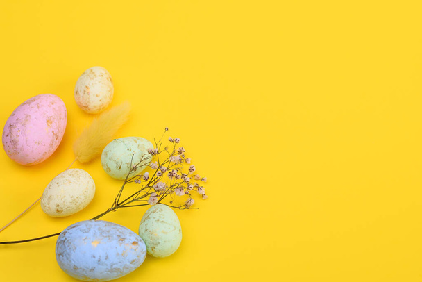 Easter eggs, a sprig of gypsophila, a lagurus on a yellow background. free space - Foto, Imagen