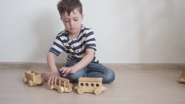 4k. Ragazzino che gioca con il treno di legno. giocattoli ecologici - Filmati, video