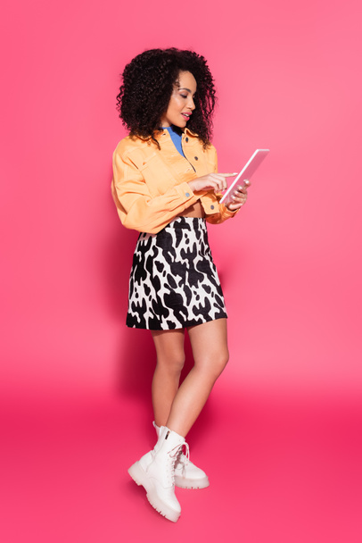 longitud completa de la mujer afroamericana utilizando tableta digital en rosa  - Foto, Imagen