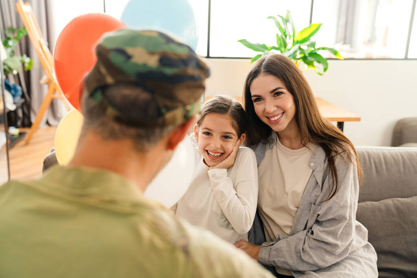 Happy kids and their mom meeting military dad in uniform indoors. Family reunion or returning home concept - 写真・画像