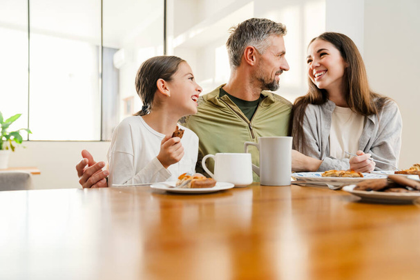 Happy masculine military man hugging his family while having breakfast indoors - Foto, afbeelding