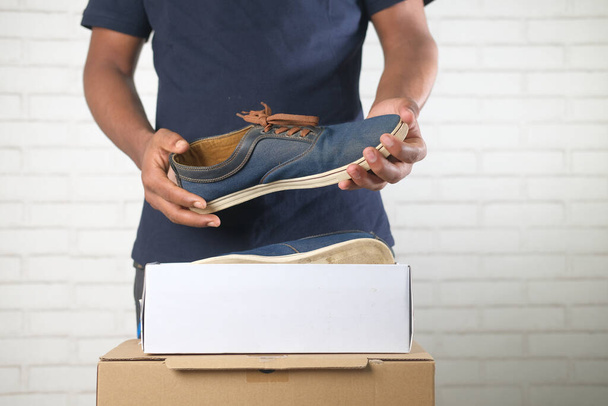 Junger Mann öffnet Schachtel für Schuhe  - Foto, Bild