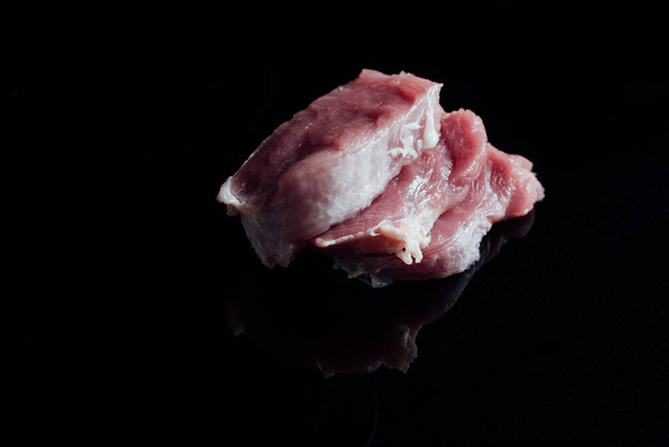 Un gros plan de filet de porc cru sur fond noir - Photo, image