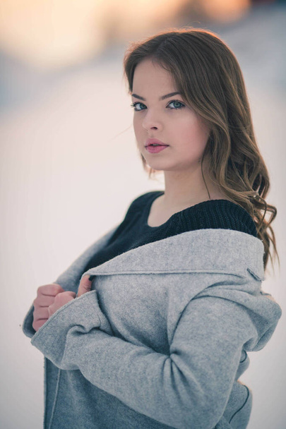 A shallow focus of a brunette woman wearing a cardigan with a sweater and posing in a forest in winter - Foto, immagini