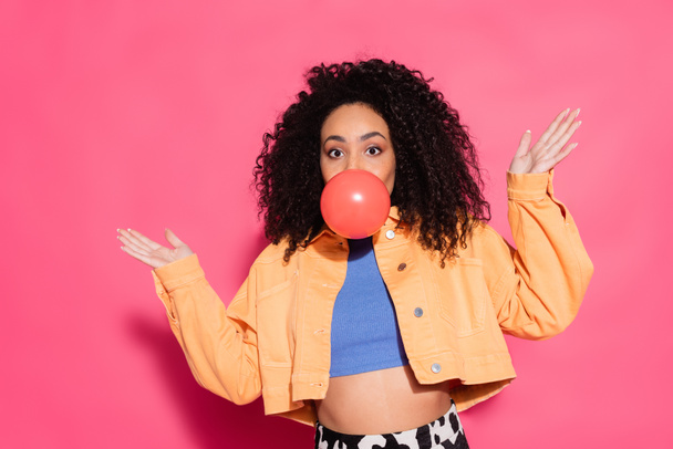 confused african american woman blowing bubble gum on pink  - Photo, Image