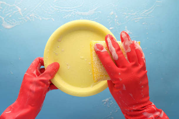 sponge , rubber gloves and colorful plate on blue  - Photo, Image