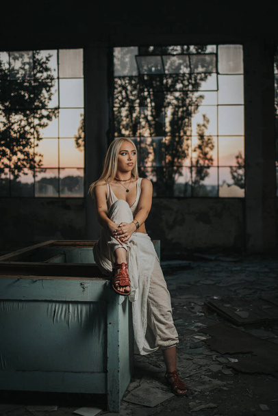 A vertical shot of a sexy Bosnian blonde woman wearing a crop top posing in an abandoned building - Photo, image