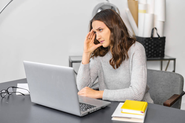 Worried female office employee with a laptop - Fotoğraf, Görsel