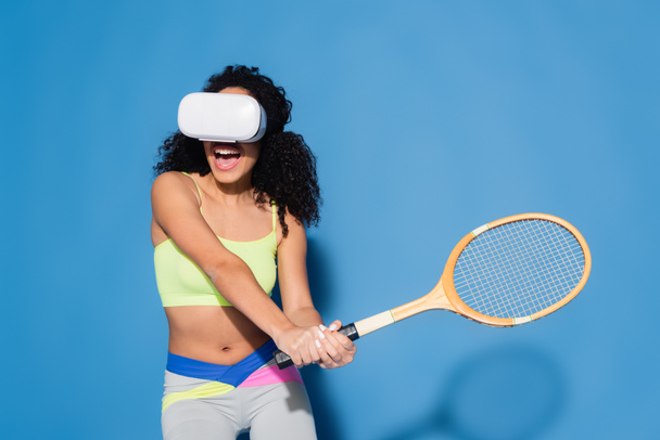 amazed african american woman in vr headset playing tennis on blue - Photo, Image