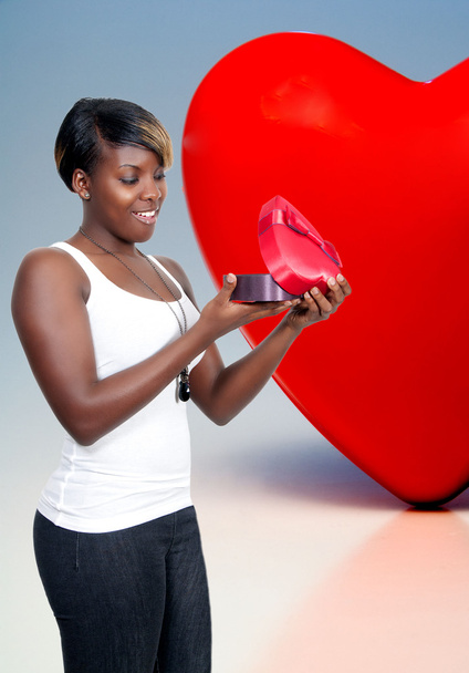 A gyönyörű fiatal fekete afro-amerikai nő, kezében egy Valentin nap szív doboz ajándék jelen - Fotó, kép