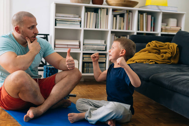father and son talking after exercise at home - Фото, зображення
