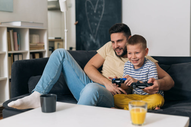 father playing video games with his son at home - Фото, изображение