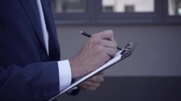 Cropped view of businessman writing on clipboard outdoors - Footage, Video