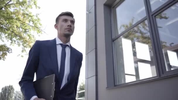 Businessman with clipboard walking outdoors - Footage, Video