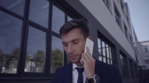 Homme d'affaires en lunettes de soleil parlant sur smartphone en plein air  - Séquence, vidéo