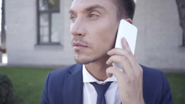 Улыбающийся бизнесмен разговаривает по смартфону на улице  - Кадры, видео