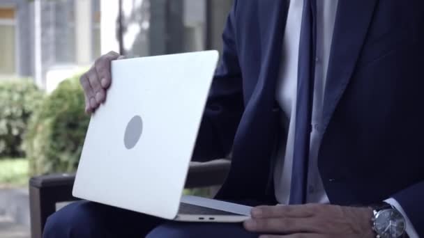 Homme d'affaires en costume en utilisant un ordinateur portable et assis sur le banc  - Séquence, vidéo