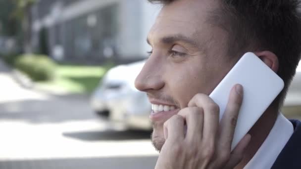 Πλευρική άποψη του επιχειρηματία μιλώντας στο κινητό τηλέφωνο σε εξωτερικούς χώρους  - Πλάνα, βίντεο