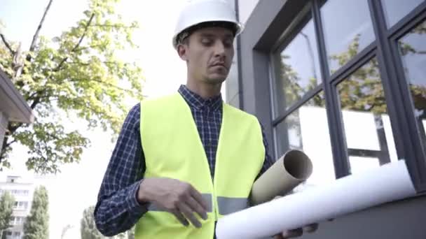 Építő tervrajzzal séta az épület közelében  - Felvétel, videó
