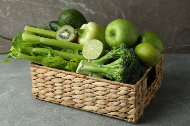 Basket with green vegetables on gray table - Foto, imagen
