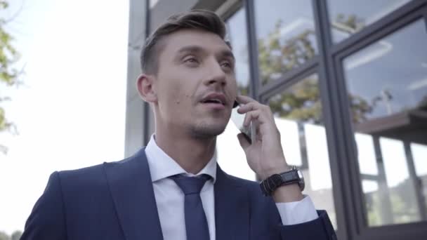 Manager w garniturze rozmawia przez telefon komórkowy na zewnątrz  - Materiał filmowy, wideo