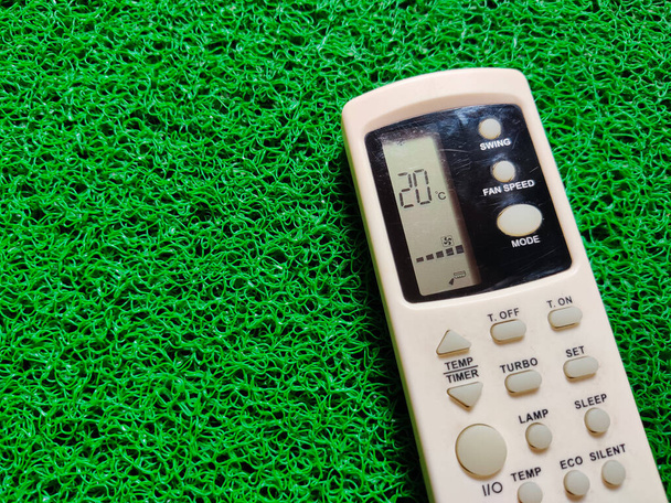 White color Air conditioner (AC) remote with a temperature of 20 degree celsius. Isolated on green background - Photo, Image