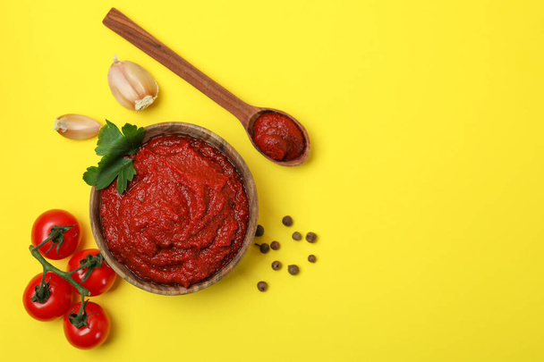 Schaal van tomatenpasta en ingrediënten op gele achtergrond - Foto, afbeelding