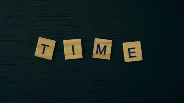 The word TIME is constructed from letter-shaped wooden cube tiles. Stop motion. - Footage, Video