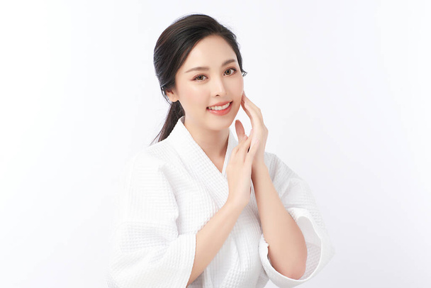Hermosa mujer asiática joven con albornoz sobre fondo blanco, Cuidado de la cara, Tratamiento facial, Cosmetología, belleza y spa Concepto. - Foto, Imagen