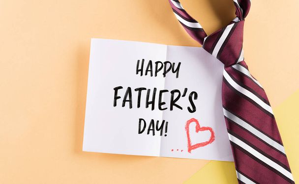 Šťastný Den otců nápis ve slavné pohlednici a kostkované kravatě na pastelovém pozadí - Fotografie, Obrázek