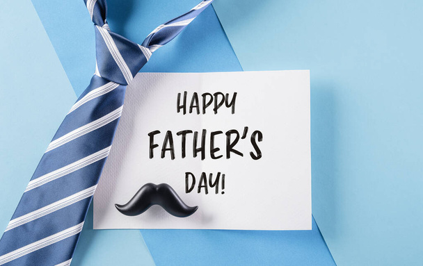 Happy Father's Day inscription in celebrated card and plaid tie on pastel blue background - Фото, зображення
