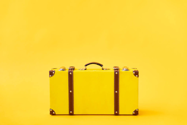 Vintage suitcase against yellow background. Summer vacation and travel concept - Photo, image