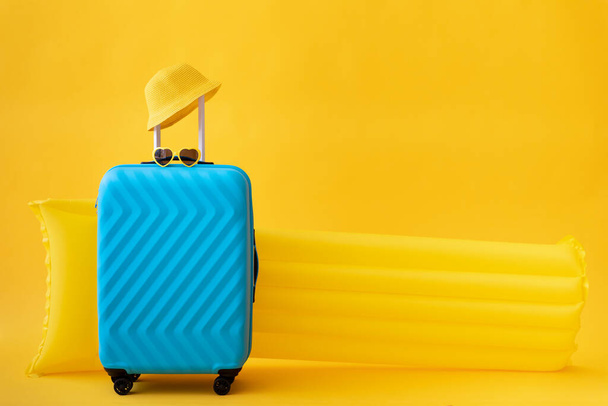 Blue suitcase against yellow background. Summer vacation and travel concept - Valokuva, kuva