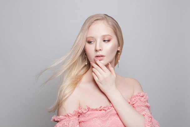 Милая молодая женщина с светлыми волосами и розовыми маникюрами ногтей на белом фоне - Фото, изображение