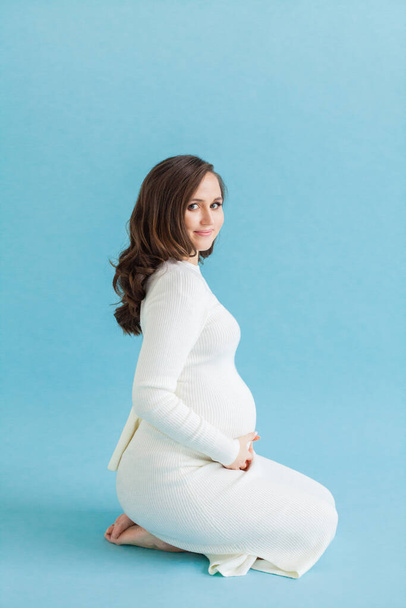 Porträt einer hübschen schwangeren Frau auf blauem Hintergrund - Foto, Bild