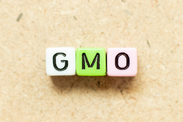 Kolor bloku liter alfabetu w słowie GMO (skrót od organizmów zmodyfikowanych genetycznie) na tle drewna - Zdjęcie, obraz
