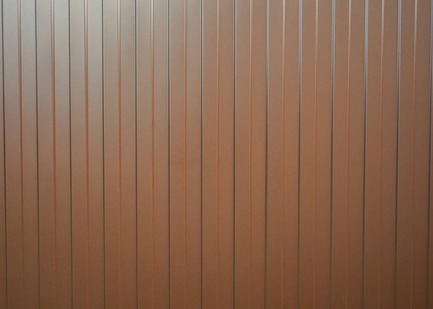 Golfplaat verticale metalen textuur achtergrond. De textuur van het metalen hek van het profiel bruin blad met verticale lijnen - Foto, afbeelding