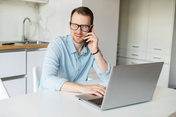 Smart young businessman talks on the phone using laptop - Foto, imagen
