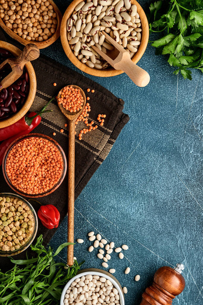 Legumes, lentils, chickpea, beans assortment, tasty appetizing ingredients spices grocery for cooking healthy kitchen on blue table. Weight loss diet and fight against cholesterol concept. Top view. - Fotoğraf, Görsel