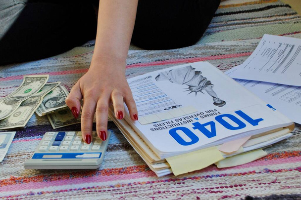 Blízká žena vypočítá individuální daňové přiznání s 1040 formuláři a pokyny. Koncept daňového přiznání. Zaplatit co nejmenší daň. - Fotografie, Obrázek