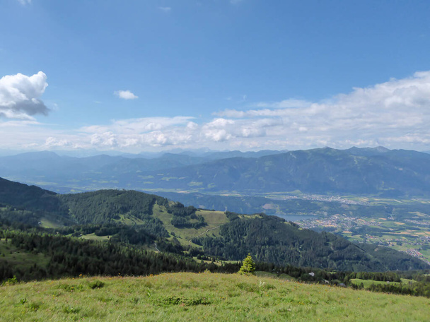 A vista panorâmica sobre o vasto vale com algumas cidades vistas de um exuberante pasto verde nos Alpes austríacos. Caminhadas nos Alpes. Exploração e descoberta. Muitas cadeias montanhosas. Paisagem intocada - Foto, Imagem