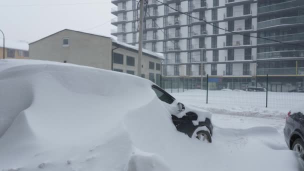 Auta pokrytá sněhem po sněhové bouři. Obytná budova v pozadí. Zpomalený pohyb - Záběry, video