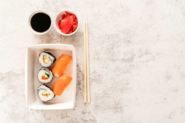 Concepto de cocina japonesa. Set de sushi con sopas de soja, jengibre y chopstics sobre fondo de mármol blanco. Vista superior. Acostado. espacio de copia - Foto, Imagen